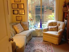 a living room filled with furniture next to a window covered in framed pictures on the wall