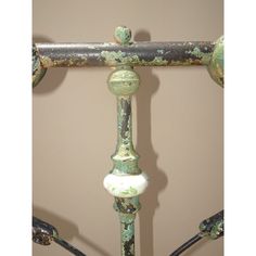 an old iron bed frame with rusted green paint and white knobs on it