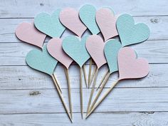 several heart shaped wooden picks in pastel blue, pink and green on a white wood background