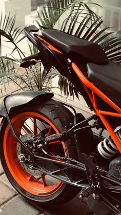 an orange and black motorcycle parked on the sidewalk