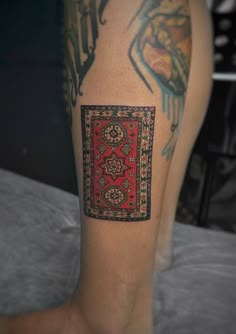 a woman's leg with tattoos on it and a red square in the middle