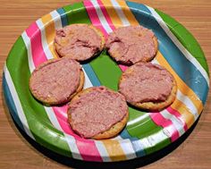 several hamburger patties are on a plate with a striped tablecloth and wooden table