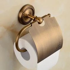 an antique brass toilet paper holder on the wall with a roll of toilet paper hanging from it