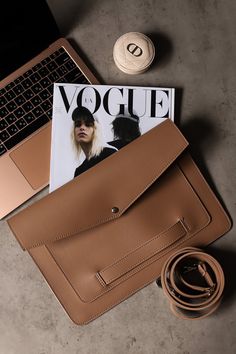 a brown purse sitting on top of a table next to a laptop computer and magazine