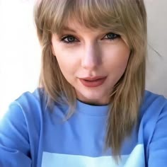 a close up of a person wearing a blue shirt and posing for a photo with her hand on her head