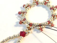 a pair of beaded bracelets sitting on top of a white table next to pins