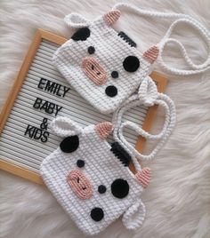 two crocheted cow purses sitting on top of a white fur covered floor