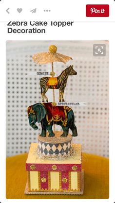 an elephant and zebra figurine sitting on top of a small box with a umbrella