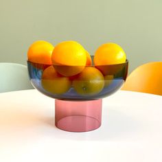 a glass bowl filled with oranges on top of a table