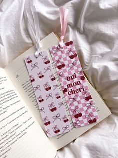 two bookmarks with words on them are laying next to an open book that says oui non cher