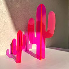 a pink sculpture sitting on top of a white table next to a cactus shaped object