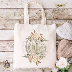 a tote bag sitting on top of a wooden table next to a hat and flowers