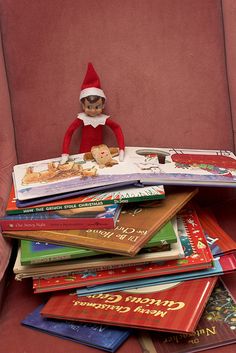 a stack of books sitting on top of a red chair next to a stuffed animal