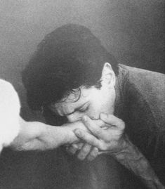 a black and white photo of a man holding his hands over the face of a cat