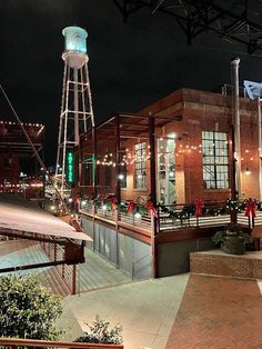 an old brick building with lights on and a water tower in the background