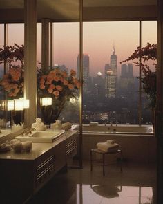 a bathroom with two sinks and large windows looking out at the cityscape in the distance