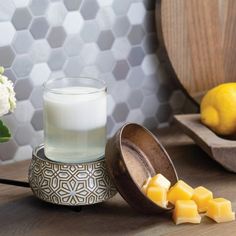 a glass of milk next to sliced lemons on a wooden table with hexagonal tiles in the background