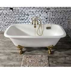 a white bath tub sitting on top of a wooden floor next to a brick wall