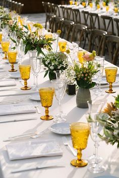 a long table is set with yellow glasses and place settings for the guests to sit down