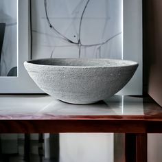 a stone bowl sitting on top of a wooden table next to a framed photo and artwork