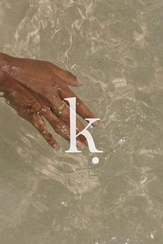 a person's hand reaching for the letter k in water