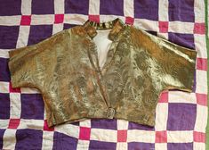 This amazing  1930s Lame bolero is in excellent condition considering its age.No major issue but light signs of age and use should be expected . Overall Strong, clean and very wearable. Please study all the images carefully and zoom them for clearer details as they are part of the description. A truly beautiful historical wearable art.  One size fits many depending on your body frame and desired look.Loose fitting style. Please check lay-flat measurements in the last  image.The tape measure is i Vintage Gold Top For Formal Occasions, Vintage Gold Fitted Blouse, Fitted Vintage Gold Blouse, Fitted Vintage Costume Top, Vintage Fitted Top For Costumes, Fitted Gold Vintage Blouse, Vintage Fall Costume Top, Art Deco Glamour, Gold Lame