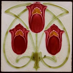 three red flowers with green stems on a white tile wall ornament in the shape of a flower