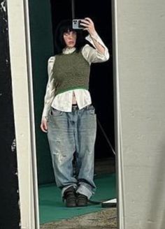 a woman taking a selfie in front of a door with her cell phone up to her ear