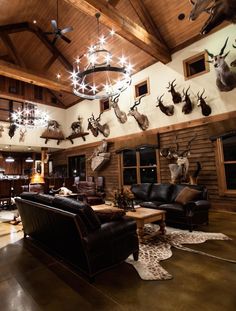 a living room filled with furniture and deer heads mounted to the wall on the walls