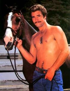 a shirtless man standing next to a brown and white horse with his hand on the bridle