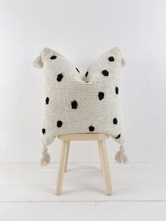 a black and white pillow sitting on top of a wooden stool