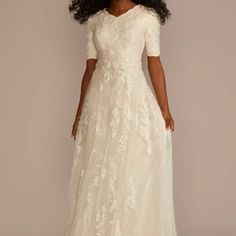 a woman in a white wedding dress with an open back and short sleeves, standing against a