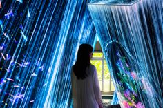 a woman standing in front of an art installation with blue lights on the walls and ceiling