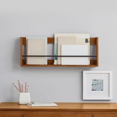 a wooden desk topped with a shelf filled with books and papers next to a framed photograph