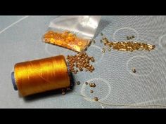 an orange spool of thread next to some gold flakes