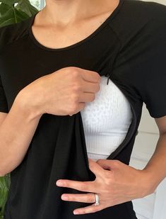 a woman wearing a black shirt and white top is holding her hand on the pocket