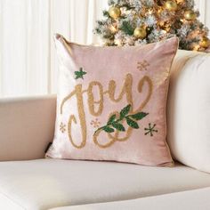 a pink pillow sitting on top of a couch next to a christmas tree