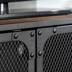 an old television is sitting on top of a wooden table with metal rivets