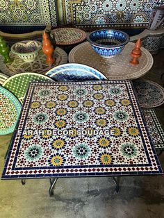 several plates and bowls are on display in a room with mosaic tile walls, flooring and tables