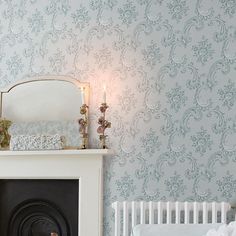 a fireplace with a mirror on top of it next to a wallpapered wall