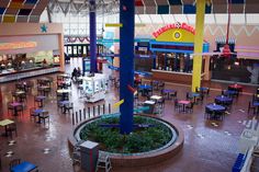 the inside of a mall with tables, chairs and benches in it's center