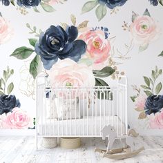 a white crib in front of a floral wallpaper with blue and pink flowers