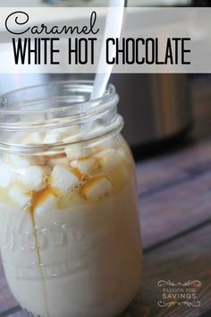 a jar filled with white hot chocolate on top of a wooden table