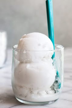 two scoops of ice cream sit in a glass cup on a marble countertop