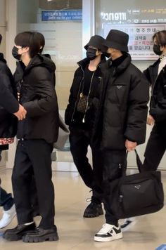 group of people in black coats and hats standing together with luggage bags on their backs