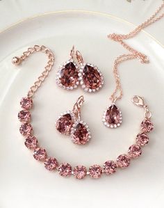 a necklace and earring set with pink stones on a white plate next to flowers