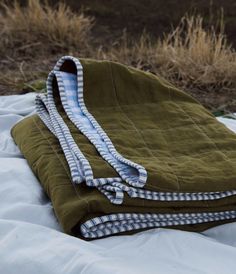 an unmade blanket laying on top of a bed in the middle of a field