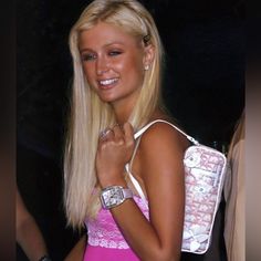 a woman in a pink dress is holding a white purse and smiling at the camera