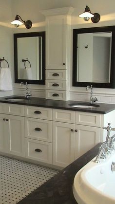 two sinks and mirrors in a bathroom with white cabinets, black counter tops and drawers