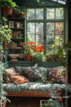 a room filled with lots of potted plants next to a window covered in books